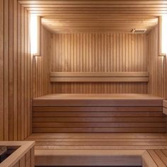 the inside of a wooden sauna with two benches and lights on each side of it