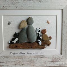 there are three rocks and two cats sitting on top of each other in a white frame