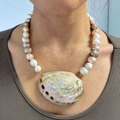 "Shell queen " This is a beautiful statement necklace made of chunky mop shell pearl beads . They have various colours mixed white, creamy and pink .  It is decorated with an xl  large  natural shell .  It is an impressive piece for extra ordinary looks . An ideal mermaid aesthetic piece Oval mop beads size aprox: 1x1.8 cm Irregular mop shell beads size aprox : 1.5-2 cm  Shell pendant length aprox 6-6.5  c/m  Necklace total length . one size / adjustable length .  Hypoallergenic/ sensitive frien Handmade Mother Of Pearl Shell Necklaces, Handmade White Shell-shaped Pearl Necklace, Pearl White Mother Of Pearl Shell Necklace Gift, Pearl White Mother Of Pearl Shell Necklace As Gift, White Mother Of Pearl Pendant Shell Necklace, Unique Mother Of Pearl Shell Necklace Gift, Handmade Shell-shaped Pearl Necklace, Handmade Shell-shaped Pearl Necklace Gift, Handmade Shell-shaped Pearl Necklace For Gift