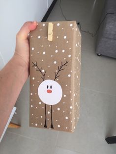 a person holding up a brown paper bag with reindeer on it