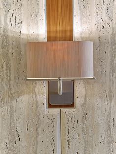 a wall mounted light with a wooden shade on it's side and a mirror above it