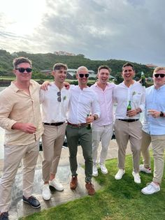 a group of men standing next to each other on top of a lush green field