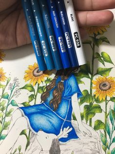 a person holding four blue markers in their hand next to a drawing of a girl and sunflowers