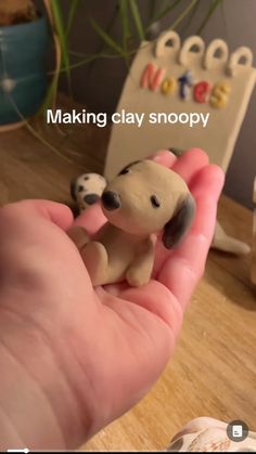 a person holding a small toy dog in their hand with the caption making clay snoopy