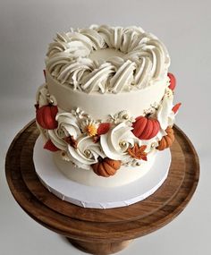 a three tiered cake with white frosting and orange flowers on a wooden stand