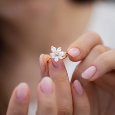 a close up of a person's hand holding a ring with a flower on it