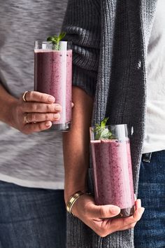 two people holding glasses with smoothies in them