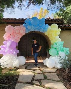 a man standing in front of a arch made out of balloons