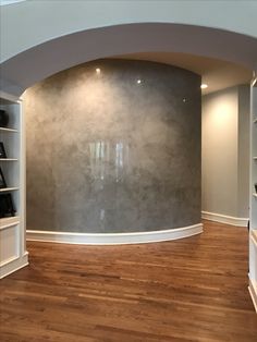 an empty room with wood floors and white shelves on either side of the round wall