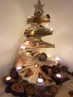 a christmas tree made out of wood with candles on the bottom and pine cones around it