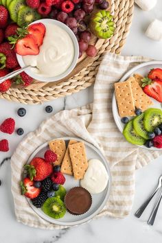 two plates filled with fruit and crackers on top of a table