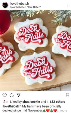 four decorated cookies sitting on top of a wooden tray next to a red ornament