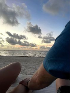 two people are sitting on a boat looking out at the water and clouds in the sky