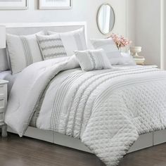 a bed with white comforter and pillows in a room