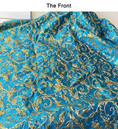 the front of a blue and gold brocaded fabric with an intricate design on it