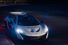 a white sports car driving down a street at night