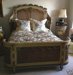 a bed with many pillows on it in a room next to a lamp and other furniture