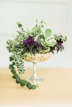 a glass vase filled with green and purple flowers