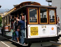 people standing on the side of a trolly car in san francisco, california usa