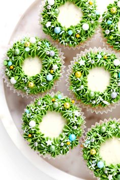 green cupcakes with white frosting and decorations on a marble platter, ready to be eaten