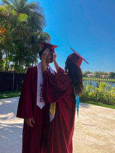 two people in graduation gowns and caps are looking at each other's eyes