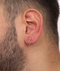 a man's ear is shown with a small gold nose ring in the shape of a snake