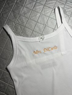 a white tank top with the word mrs picard on it sitting on a quilted bed