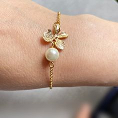 A gold plated of detailed orchid flowers is holding a small glass ivory wired pearl. The chain is gold plated and measures a standard 7", if you would like a different length just leave a note when you checkout. Orchid Necklace: https://www.etsy.com/listing/230963084/silver-necklace-orchid-necklace-flower?ref=shop_home_active_8 Orchid Necklace: https://www.etsy.com/listing/270892882/orchid-necklace-cascading-orchid?ref=listing-shop-header-0 Please visit all the items from my chop here . https:// Gold Flower Bracelets For Party, Gold Bracelets With Flower Charm For Wedding, Delicate Floral Bracelet For Formal Occasions, Delicate Gold Bracelets For Wedding, Delicate Gold Bracelets With Pearl Charm, Delicate Gold Pearl Bracelet For Formal Occasions, Gold Adjustable Chain Bracelet For Weddings, Gold Pearl Drop Bracelet As A Gift, Gold Pearl Chain Bracelet For Wedding