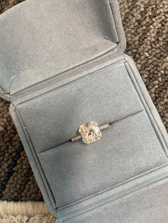 an engagement ring sitting on top of a blue velvet box