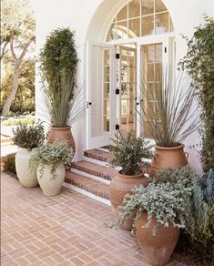 three large planters sitting on the side of a white building next to a door