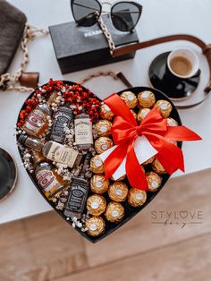 a heart shaped box filled with assorted chocolates next to a cup of coffee