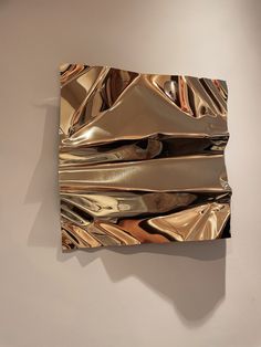 a piece of art that looks like it has been wrapped in metallic foil and is hanging on the wall