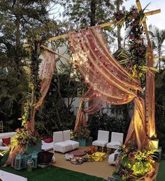 an outdoor wedding setup with white chairs and pink draping on the back wall