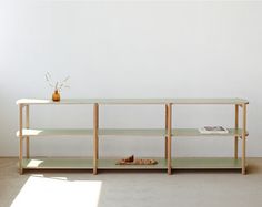 a table with two shelves and a vase sitting on top of it in front of a white wall