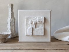 a white sculpture sitting on top of a wooden table next to a vase and bowl