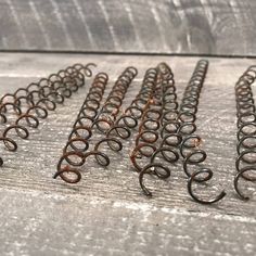 several rusty metal springs are lined up on a wooden surface, with one being held in the other direction