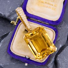 This gorgeous large dangle pendant is accented with one (1) emerald cut citrine set into a four-prong head. The hinged bail is accented with twenty-four (24), prong set, round brilliant cut diamonds. The pendant measures 54.7mm in length and 19.6mm in width. We have added an 18 inch long 14k yellow gold rounded box chain weighing approximately 3 grams. The citrine shows some light abrasion but nothing distracting. Luxury Citrine Oval Pendant Jewelry, Luxury Yellow Gold Necklace With Rectangular Stone, Luxury Yellow Gold Emerald Cut Necklace, Luxury Yellow Gold Crystal Necklace Gift, Luxury Yellow Gold Necklace With Prong Setting, Luxury Emerald Cut Gemstone With 17 Jewels, Elegant Emerald Cut Yellow Jewelry, Elegant Yellow Emerald Cut Jewelry, Citrine Fine Jewelry For Formal Occasions