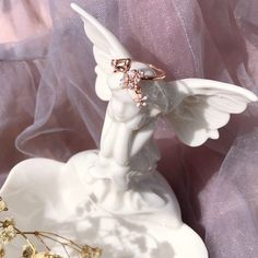 an angel figurine on a white plate with pink and gold decorations around it