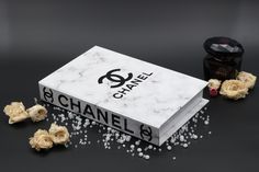 a chanel box and some flowers on a black surface with white speckles