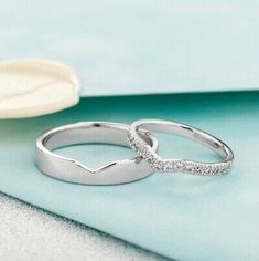 two wedding rings sitting on top of a blue cloth next to a seashell shell