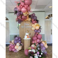 a baby shower cake surrounded by balloons and flowers