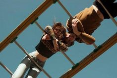 two people standing on top of a metal structure with one person holding a teddy bear