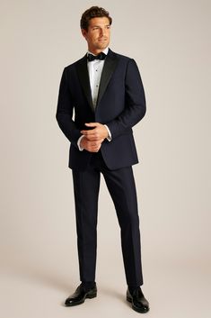 a man in a tuxedo is posing for the camera with his hands on his hips