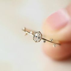 a close up of a person's hand holding a ring with a diamond on it