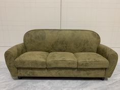 a green couch sitting on top of a marble floor next to a white tiled wall