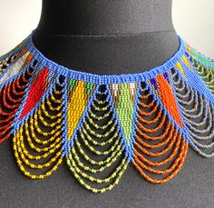 💎Absolutely stunning beaded necklace, hand made by highly skilled Zulu women in Kwa-Zulu Natal, South Africa. 💎This gorgeous necklace is made up of thousands of glass beads, each one threaded by hand to make an absolutely beautiful necklace in a crocheted look and feel. 💎Shimmering golden beads threaded throughout. 💎It is difficult to describe how beautiful this necklace is - check the images attached to view the incredible detail.   💎The necklace sits perfectly around the collarbone and li Festival Blue Beaded Necklaces With Colorful Beads, Traditional Beaded Necklaces With Bead Caps, Traditional Beaded Necklaces With Round Beads, Handmade Blue Beaded Necklaces For Festivals, Artisan Blue Beaded Necklaces For Festivals, Traditional Bib Necklace With Dangling Round Beads, Blue Beads For Festivals, Blue Beaded Necklaces For Festivals, Blue Large Beads Choker For Festival