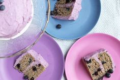 three plates with slices of cake on them and blueberries in the middle one is pink