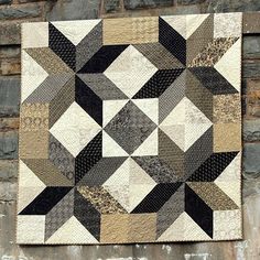 a black and white quilt hanging on a brick wall