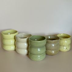 a row of different colored vases sitting on top of a white table next to each other