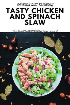 a plate with chicken and spinach salad on it next to some vegetables, nuts and leaves